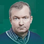 Чоловік середнього віку з сивим волоссям у синьому светрі на зеленому тлі