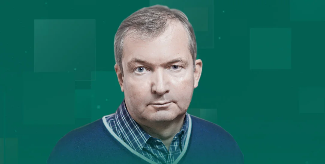 Чоловік середнього віку з сивим волоссям у синьому светрі на зеленому тлі