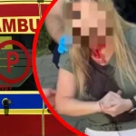 Пікселізована жінка з кров’ю на обличчі біля машини швидкої допомоги
