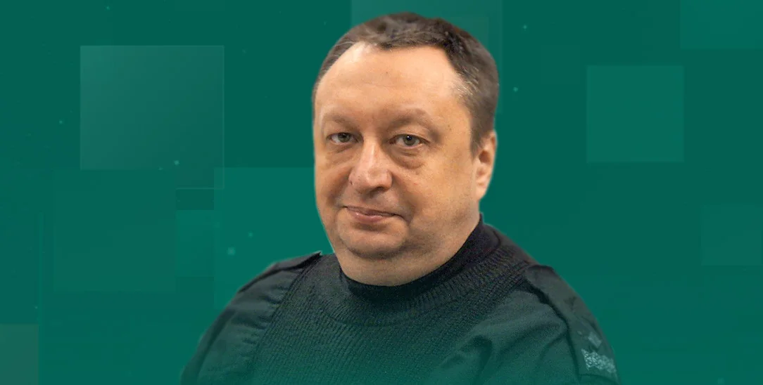 Чоловік середнього віку з коротким волоссям у чорному светері на зеленому фоні