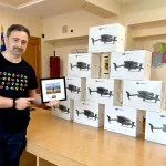 Ігор Смілянський тримає рамку біля стопки коробок дронів DJI Mavic 3 в офісі