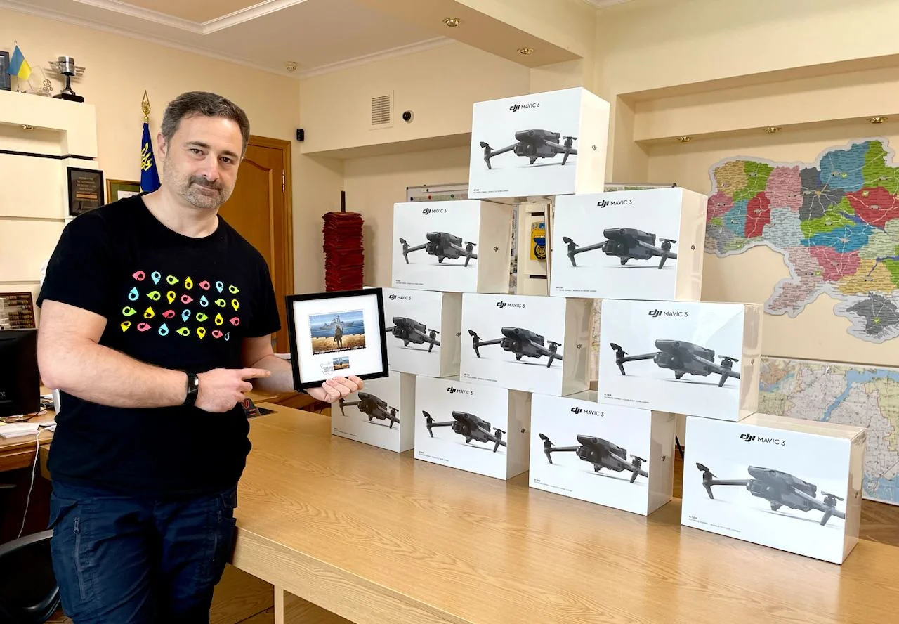 Ігор Смілянський тримає рамку біля стопки коробок дронів DJI Mavic 3 в офісі